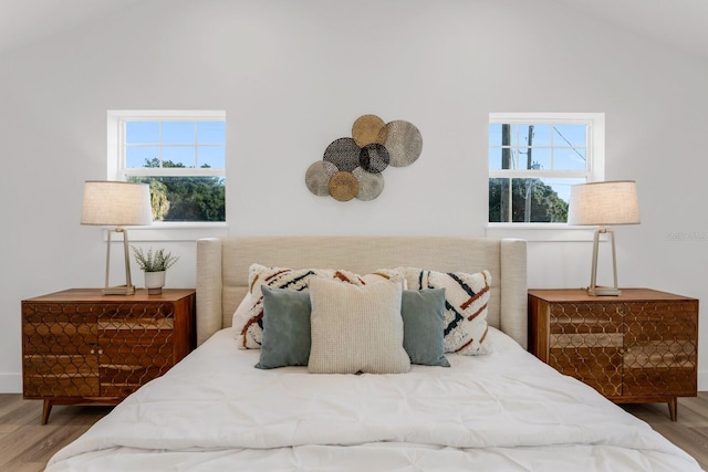 bedroom featuring hardwood / wood-style floors, multiple windows, and lofted ceiling