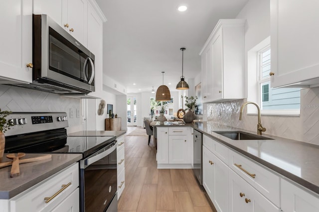 kitchen featuring a wealth of natural light, decorative light fixtures, sink, and appliances with stainless steel finishes