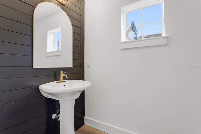 bathroom with wood walls, a healthy amount of sunlight, sink, and hardwood / wood-style flooring