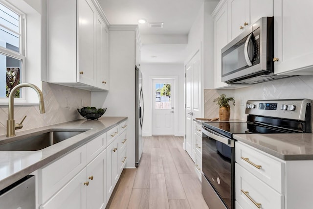 kitchen featuring light stone countertops, appliances with stainless steel finishes, white cabinetry, and sink