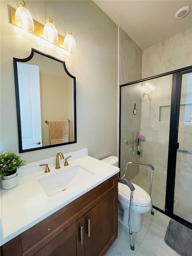 bathroom with tile patterned floors, vanity, a shower with shower door, and toilet