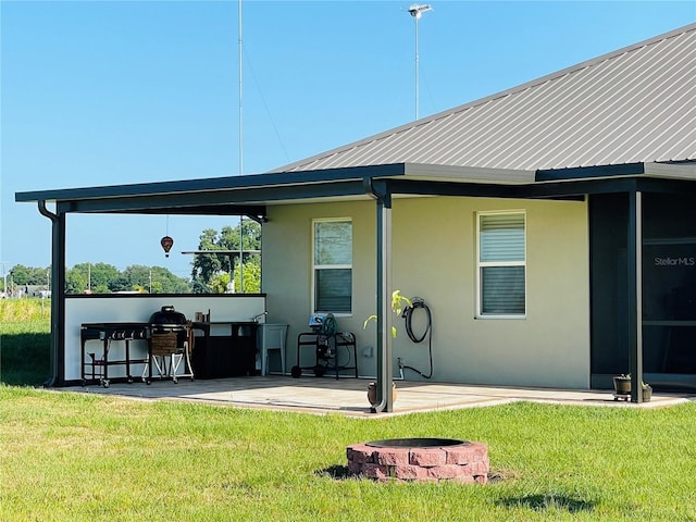 rear view of house featuring a lawn, a patio, and an outdoor fire pit