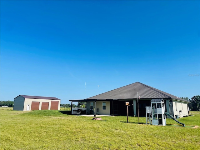 rear view of property featuring a lawn and an outbuilding