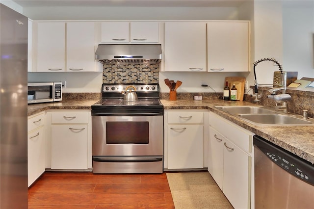 kitchen with white cabinetry, sink, wall chimney exhaust hood, appliances with stainless steel finishes, and hardwood / wood-style flooring