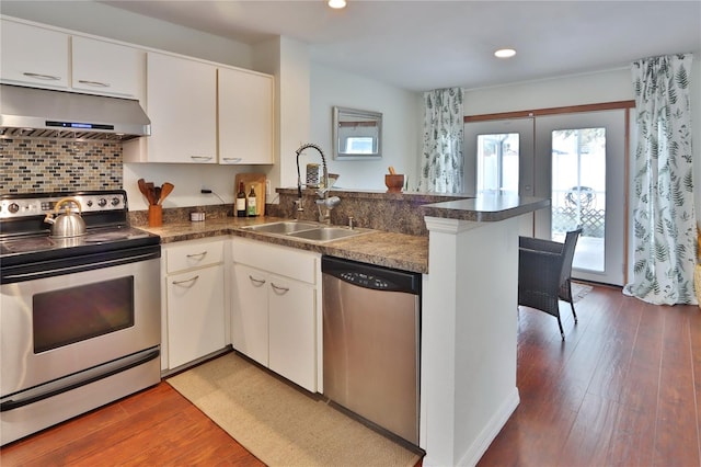 kitchen with kitchen peninsula, sink, appliances with stainless steel finishes, dark hardwood / wood-style flooring, and white cabinetry