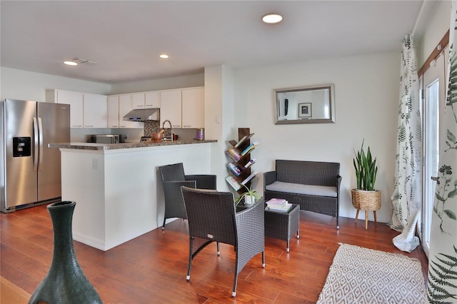 kitchen with dark hardwood / wood-style floors, white cabinetry, kitchen peninsula, and appliances with stainless steel finishes