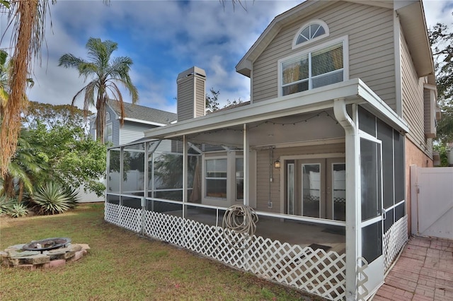 rear view of property with a yard and a fire pit