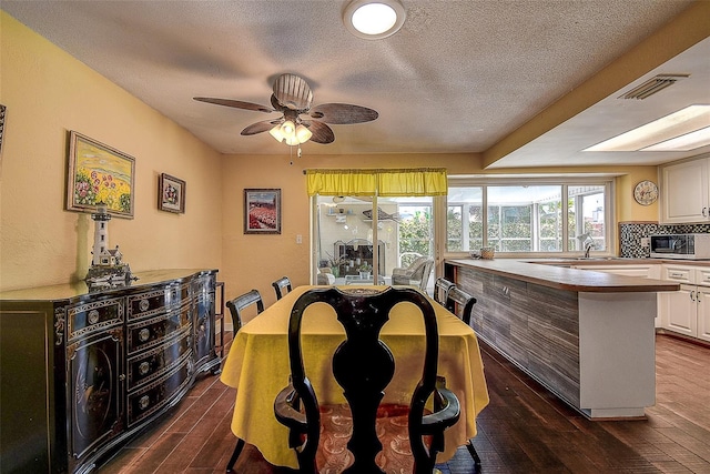 dining area with a textured ceiling, dark hardwood / wood-style floors, and ceiling fan