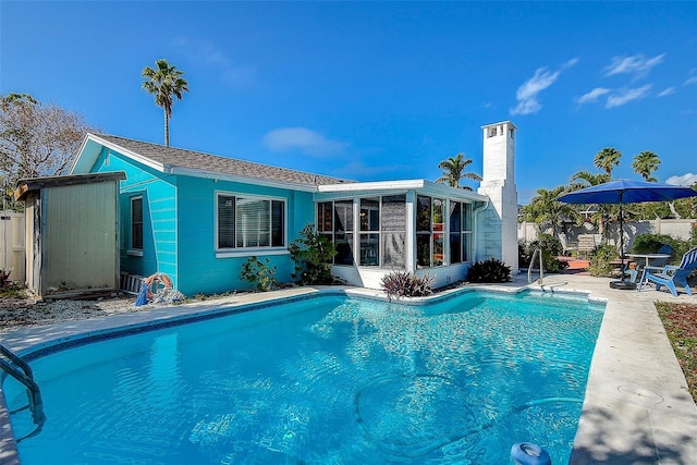 view of swimming pool with a sunroom and a patio area