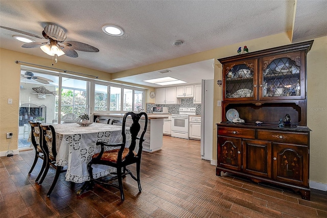 dining room with dark wood-style flooring, a textured ceiling, and baseboards