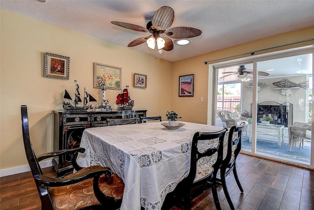 dining room featuring dark wood-style floors, a textured ceiling, a ceiling fan, and baseboards