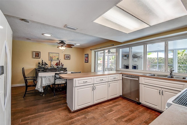 kitchen featuring white refrigerator with ice dispenser, visible vents, stainless steel dishwasher, white cabinets, and a sink