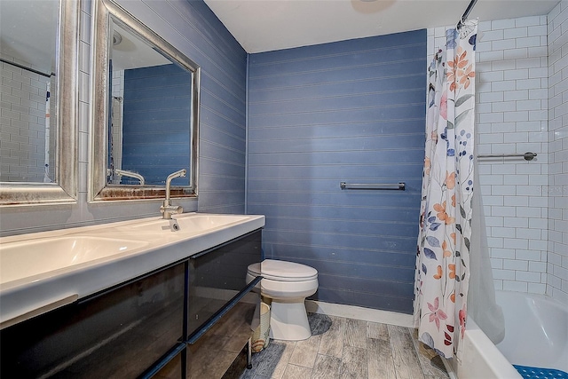 bathroom with double vanity, shower / bathtub combination with curtain, toilet, a sink, and wood finished floors