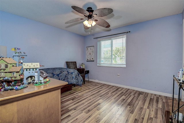 bedroom featuring a ceiling fan, baseboards, and wood finished floors