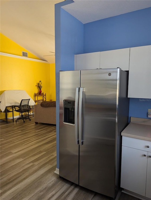 kitchen with stainless steel fridge with ice dispenser, vaulted ceiling, hardwood / wood-style flooring, and white cabinetry