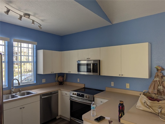 kitchen with white cabinets, rail lighting, sink, a textured ceiling, and appliances with stainless steel finishes