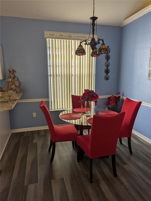 dining room with crown molding, dark wood-type flooring, and a chandelier