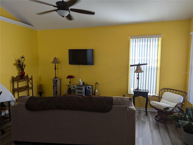 living room with lofted ceiling, crown molding, hardwood / wood-style flooring, ceiling fan, and a textured ceiling