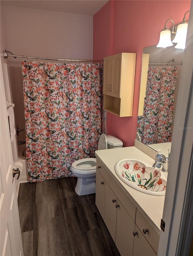 full bathroom featuring hardwood / wood-style flooring, vanity, toilet, and shower / tub combo