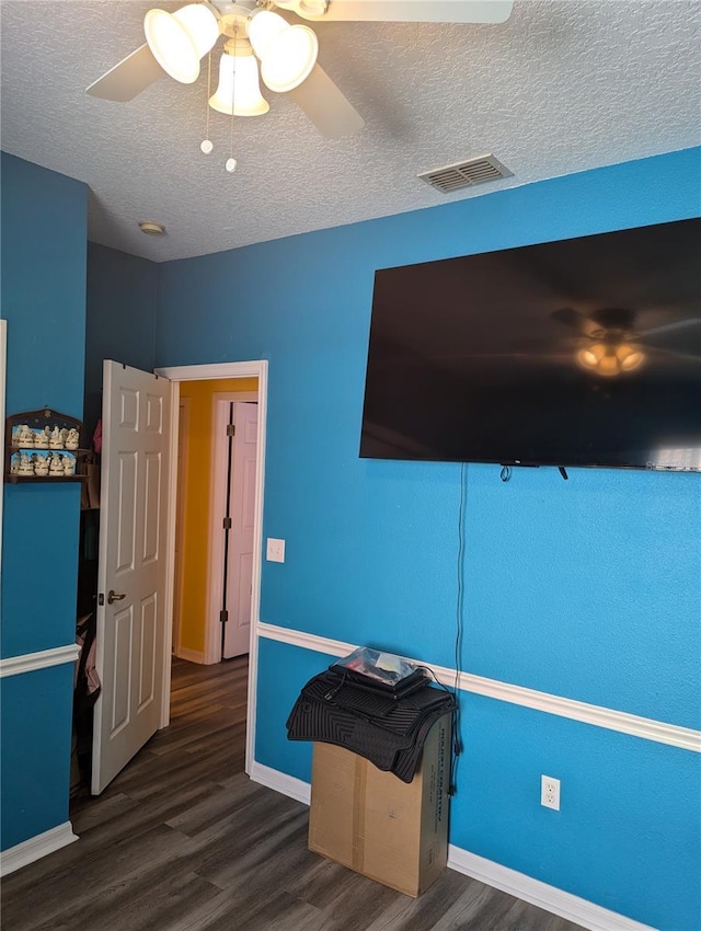 interior space featuring ceiling fan, dark wood-type flooring, and a textured ceiling