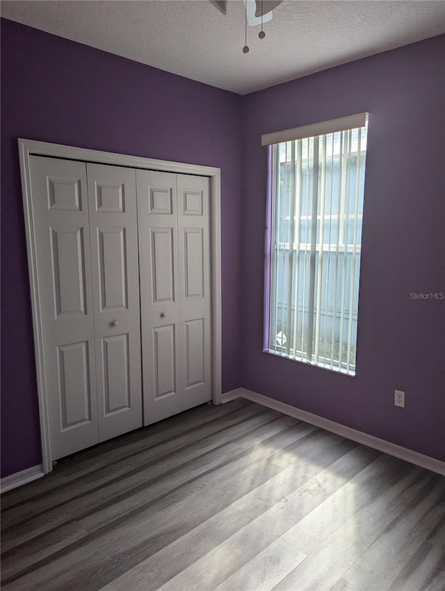 unfurnished bedroom featuring ceiling fan, a closet, a textured ceiling, and light wood-type flooring