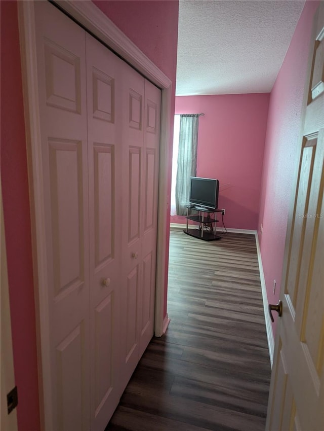 corridor with a textured ceiling and dark wood-type flooring