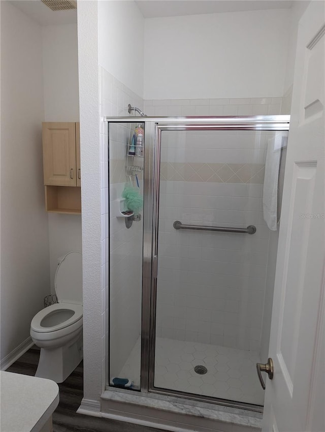 bathroom with hardwood / wood-style flooring, toilet, and an enclosed shower