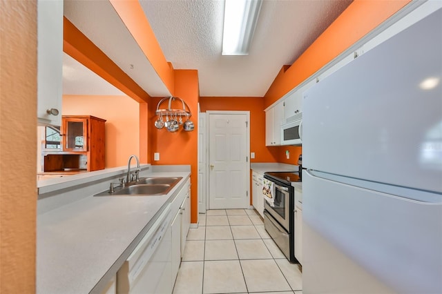 kitchen with white cabinetry, sink, light tile patterned floors, and white appliances