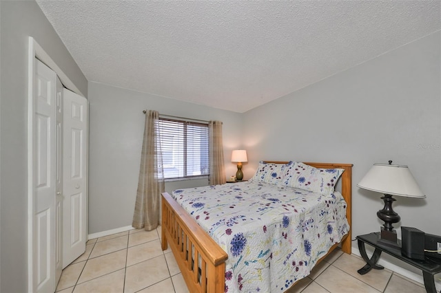 bedroom with a closet, light tile patterned floors, and a textured ceiling