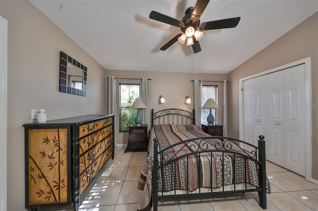 bedroom featuring a closet, ceiling fan, lofted ceiling, and light tile patterned flooring