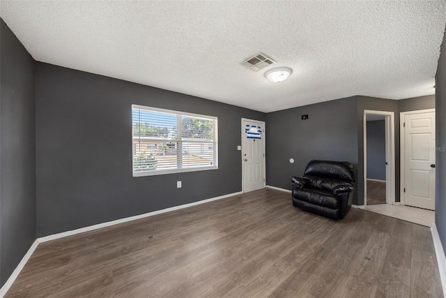 unfurnished room featuring wood-type flooring and a textured ceiling