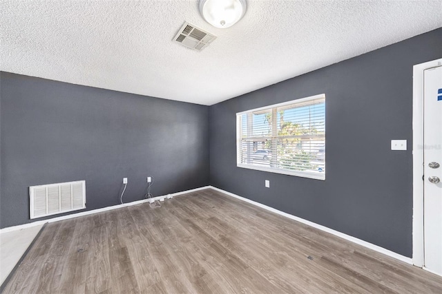 unfurnished room with hardwood / wood-style floors and a textured ceiling