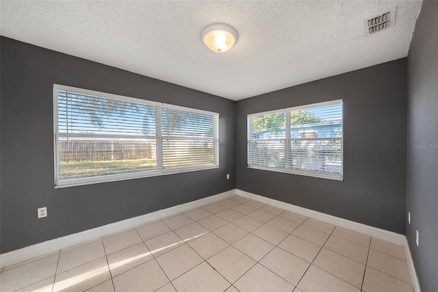 spare room featuring light tile patterned flooring and a textured ceiling