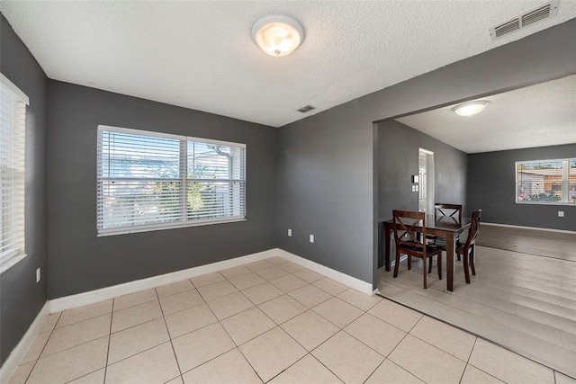 dining space featuring light tile patterned flooring and a textured ceiling