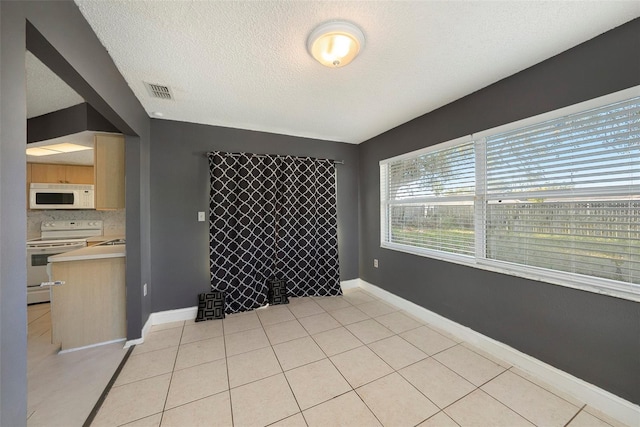 spare room featuring light tile patterned flooring and a textured ceiling