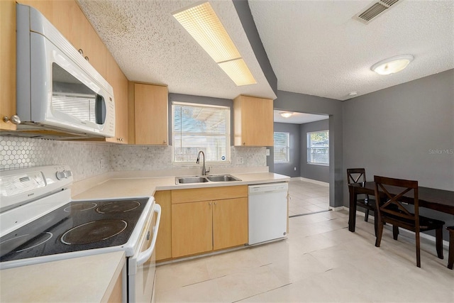 kitchen with a textured ceiling, white appliances, a healthy amount of sunlight, and sink