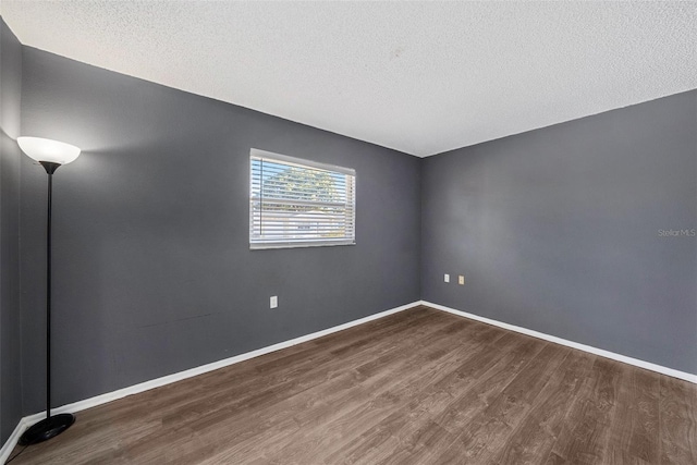 unfurnished room featuring dark wood-type flooring and a textured ceiling