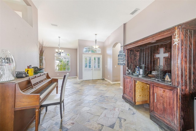 foyer featuring french doors, an inviting chandelier, and lofted ceiling