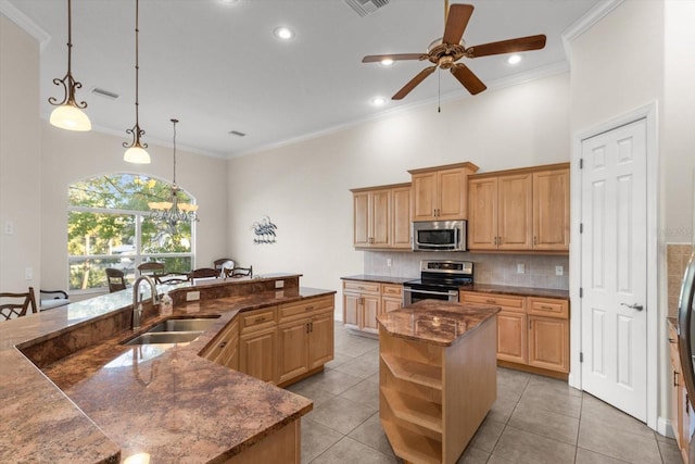 kitchen with a kitchen island with sink, sink, light tile patterned floors, appliances with stainless steel finishes, and decorative light fixtures