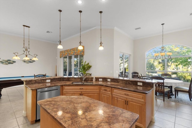 kitchen with a center island with sink, decorative light fixtures, sink, and dark stone counters