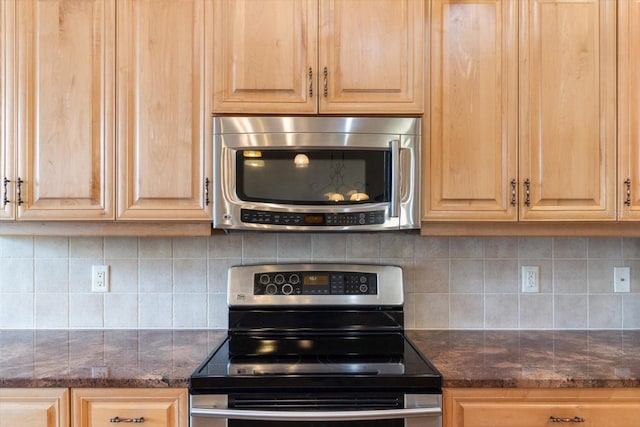 kitchen featuring backsplash, dark stone countertops, stainless steel appliances, and light brown cabinetry