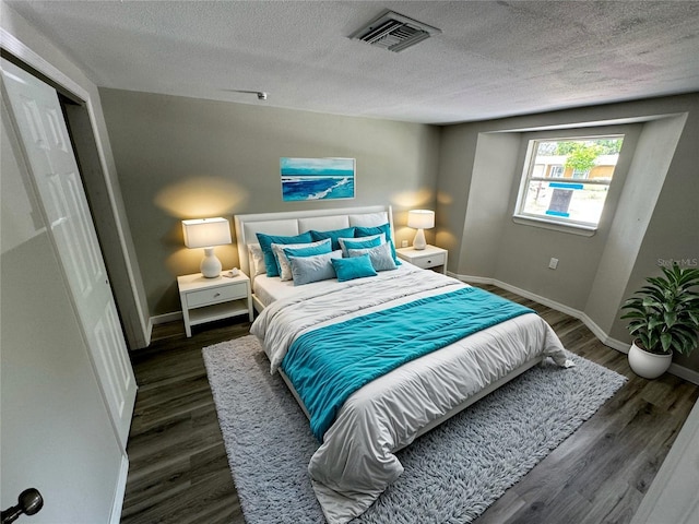 bedroom featuring dark hardwood / wood-style flooring and a textured ceiling