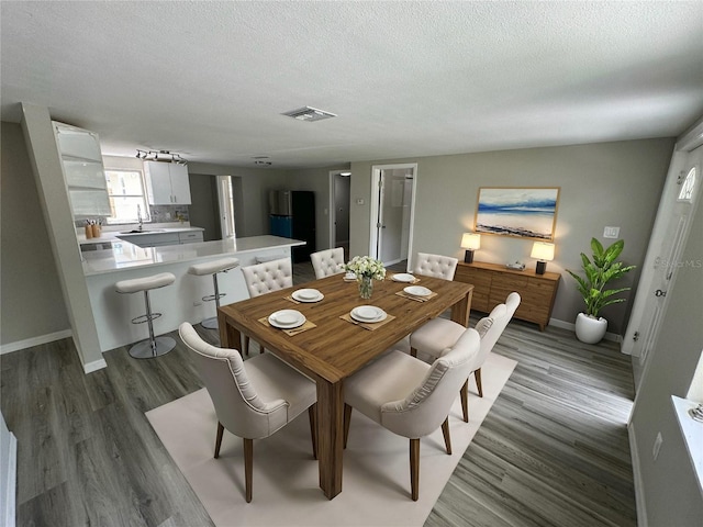 dining space with hardwood / wood-style floors, sink, and a textured ceiling