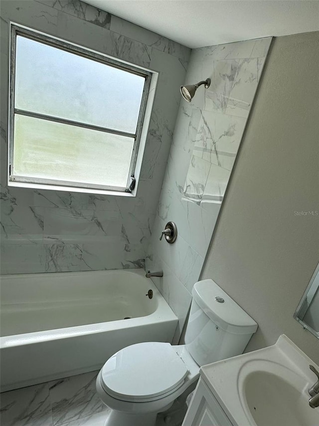 full bathroom with a wealth of natural light, toilet, vanity, and tiled shower / bath