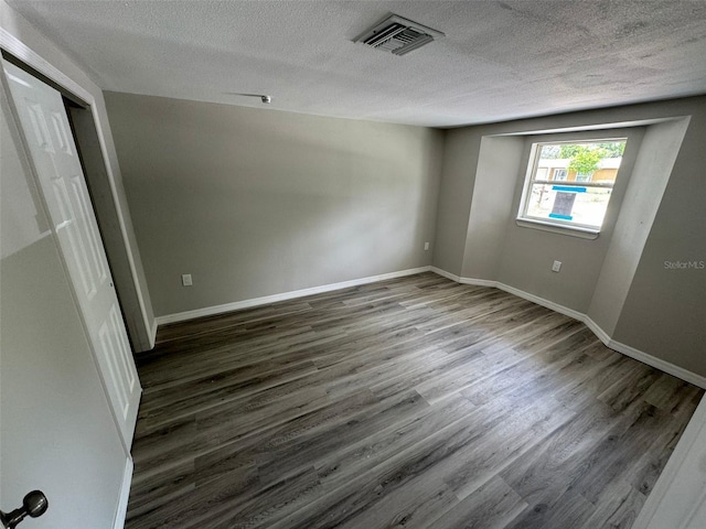 unfurnished room featuring a textured ceiling and dark hardwood / wood-style floors