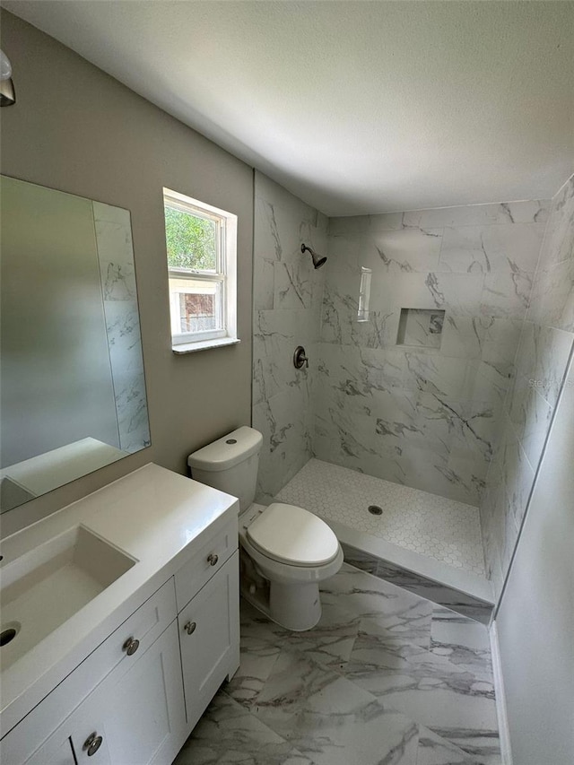 bathroom featuring toilet, vanity, and tiled shower