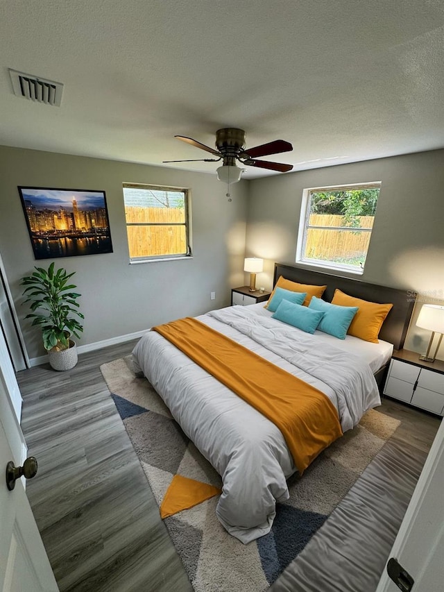 bedroom featuring a textured ceiling, wood finished floors, baseboards, and visible vents