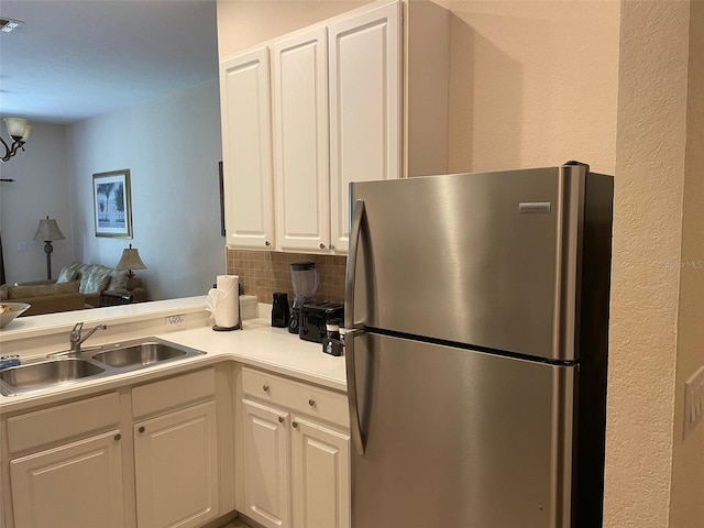 kitchen featuring decorative backsplash, white cabinetry, stainless steel refrigerator, and sink