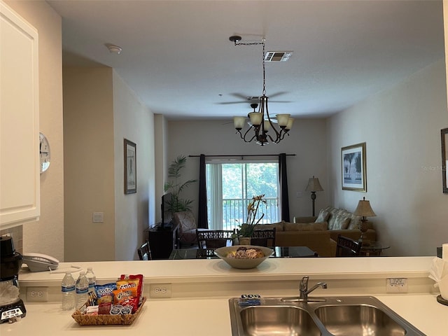 kitchen with white cabinetry, sink, and a chandelier