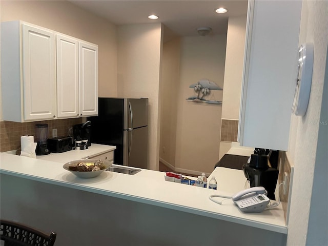 kitchen featuring tasteful backsplash, white cabinetry, and stainless steel refrigerator